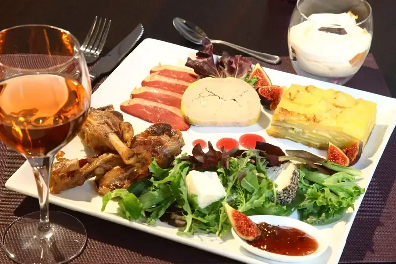 Assiette gastronomique avec canard, foie gras, gratin, salade, fromages et figues