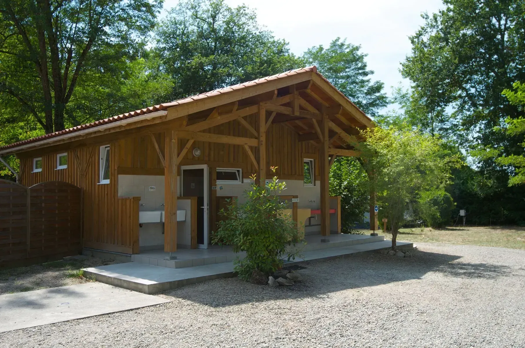 Bloc sanitaire en bois avec lavabos extérieurs et accès couverts