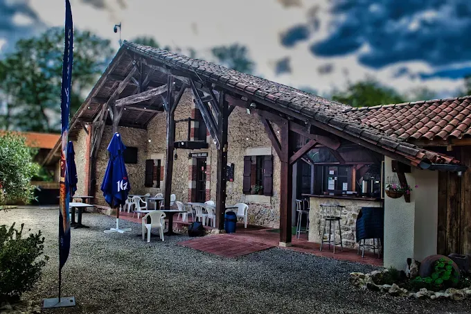 Terrasse du snack avec tables et parasols devant un bâtiment en pierre