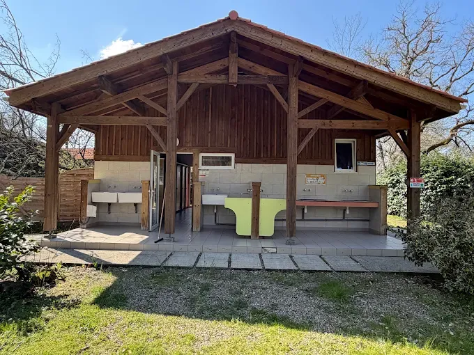 Bloc de services couvert avec bacs collectifs sous une charpente en bois